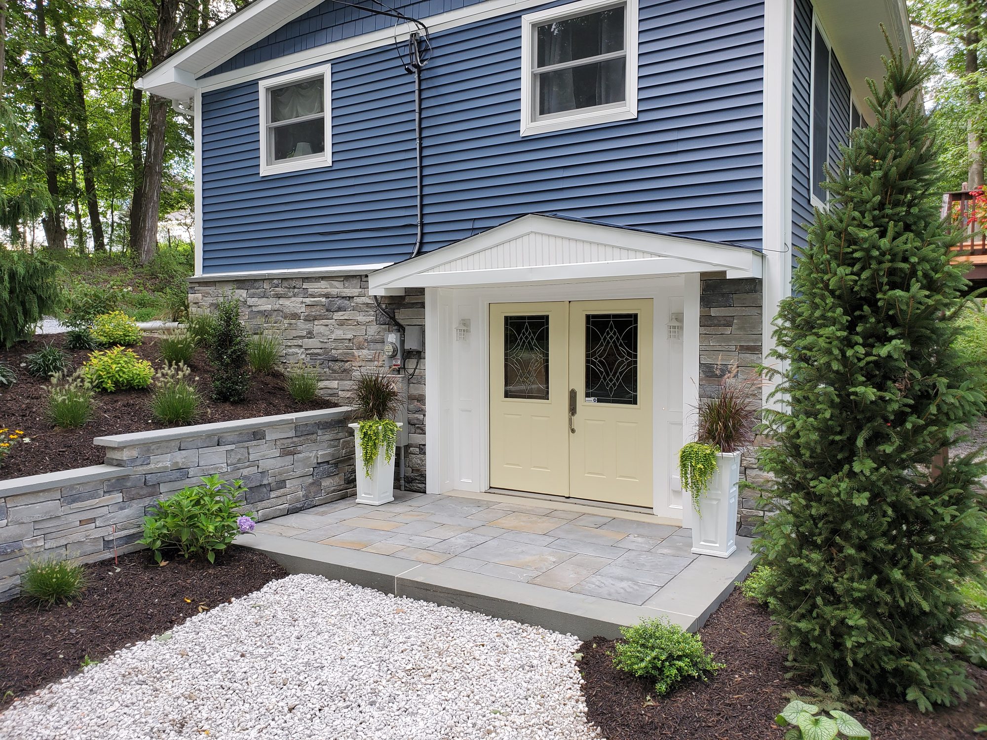 Finished exterior remodel with stone steps, patio and new plantings